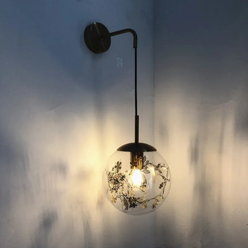 Modern glass wall lamp with metallic finish mounted beside bed for bedside lighting