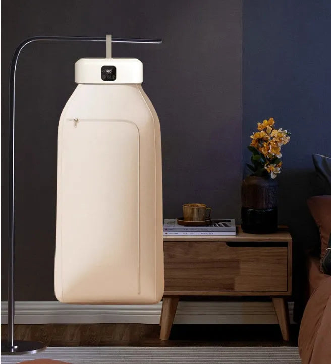 White cylindrical foldable clothes dryer with remote control on a table.