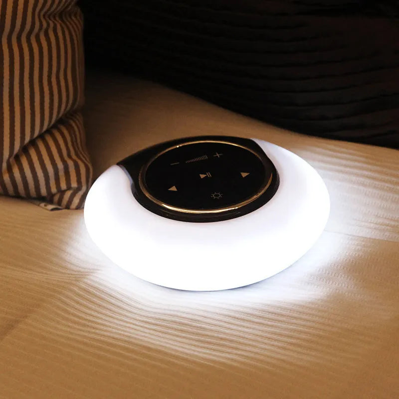 Foldable blue and white Bluetooth desk lamp with speaker, showing touch controls on a desk.