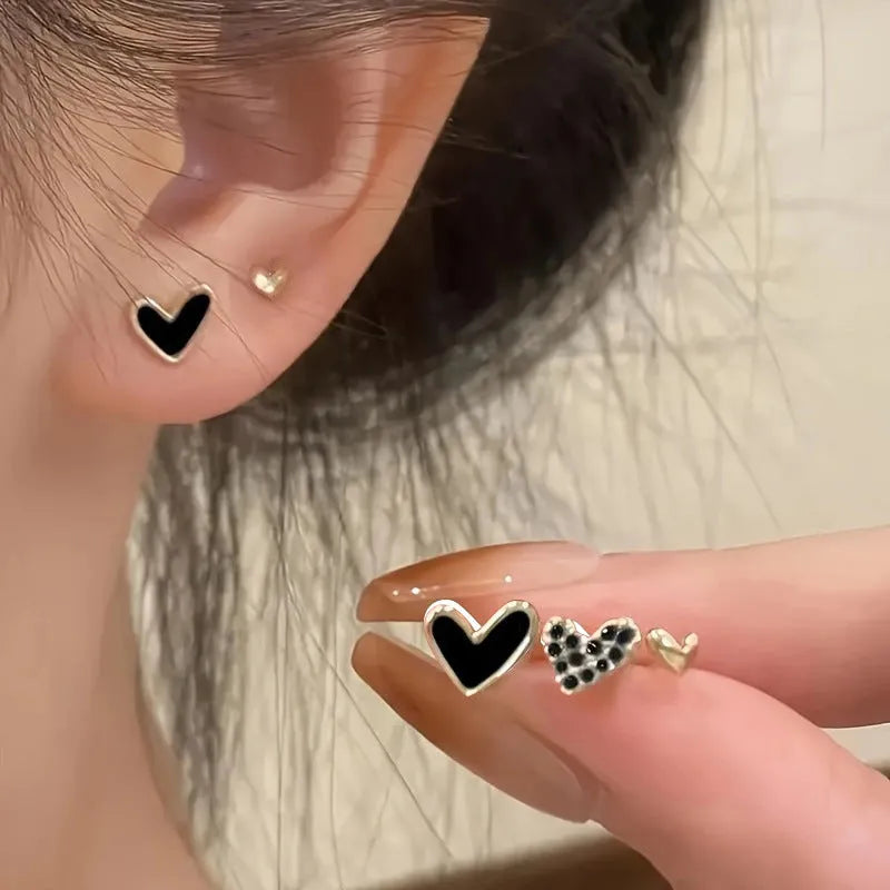 Three pairs of women's heart-shaped alloy earrings in gold, black, pink and black-white colours