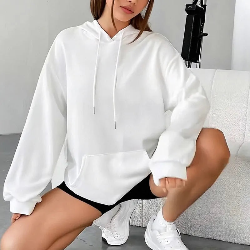 Woman wearing a loose grey sweatshirt with a front pocket and drawstring hem.
