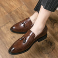 Men's black tassel slip-on loafers with a pointed toe and rubber sole on a white background.
