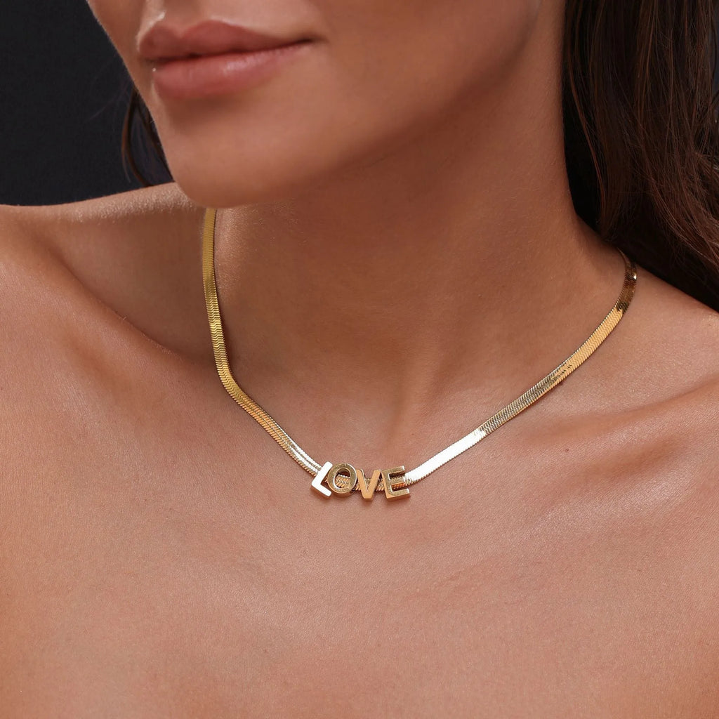 Gold electroplated titanium steel necklace with a letter A charm on a grinding chain.