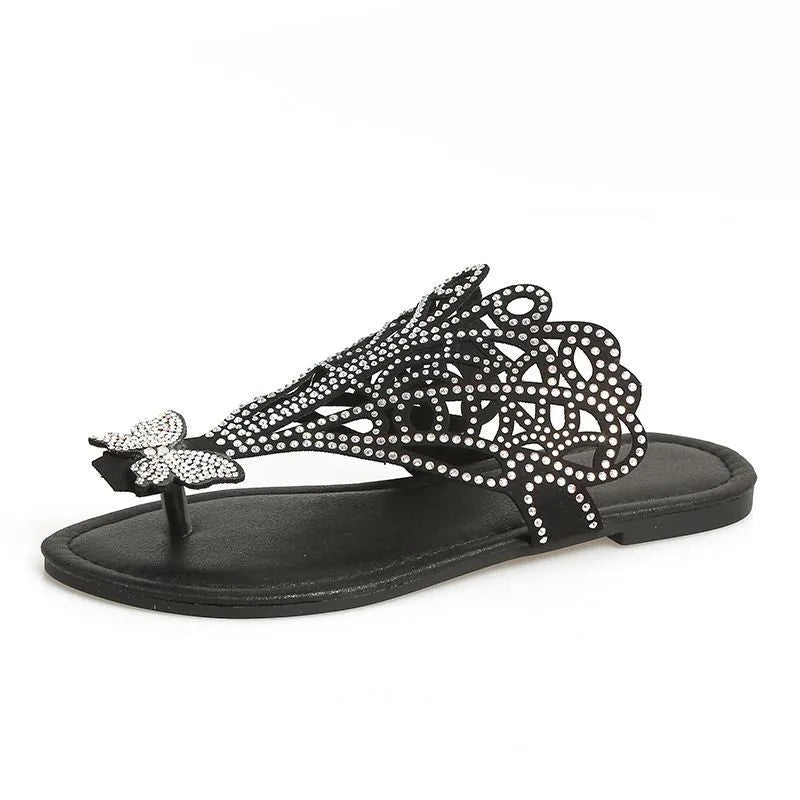 Women's black slip-on sandals with rhinestone detail and a flip-toe design on a flat rubber sole.