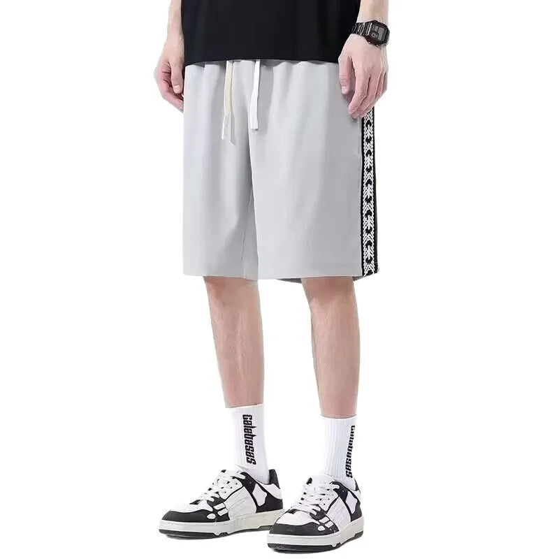 Men's black baggy track pants with elastic waistband on a neutral background.