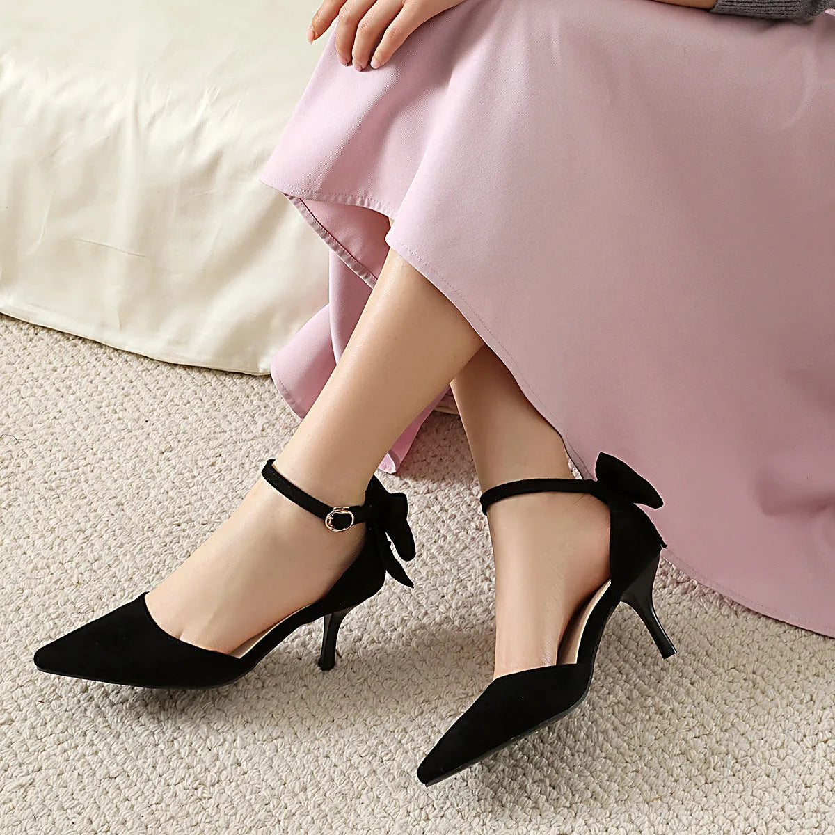 Black stiletto high heels with pointed toe and decorative bowknot detail on suede upper