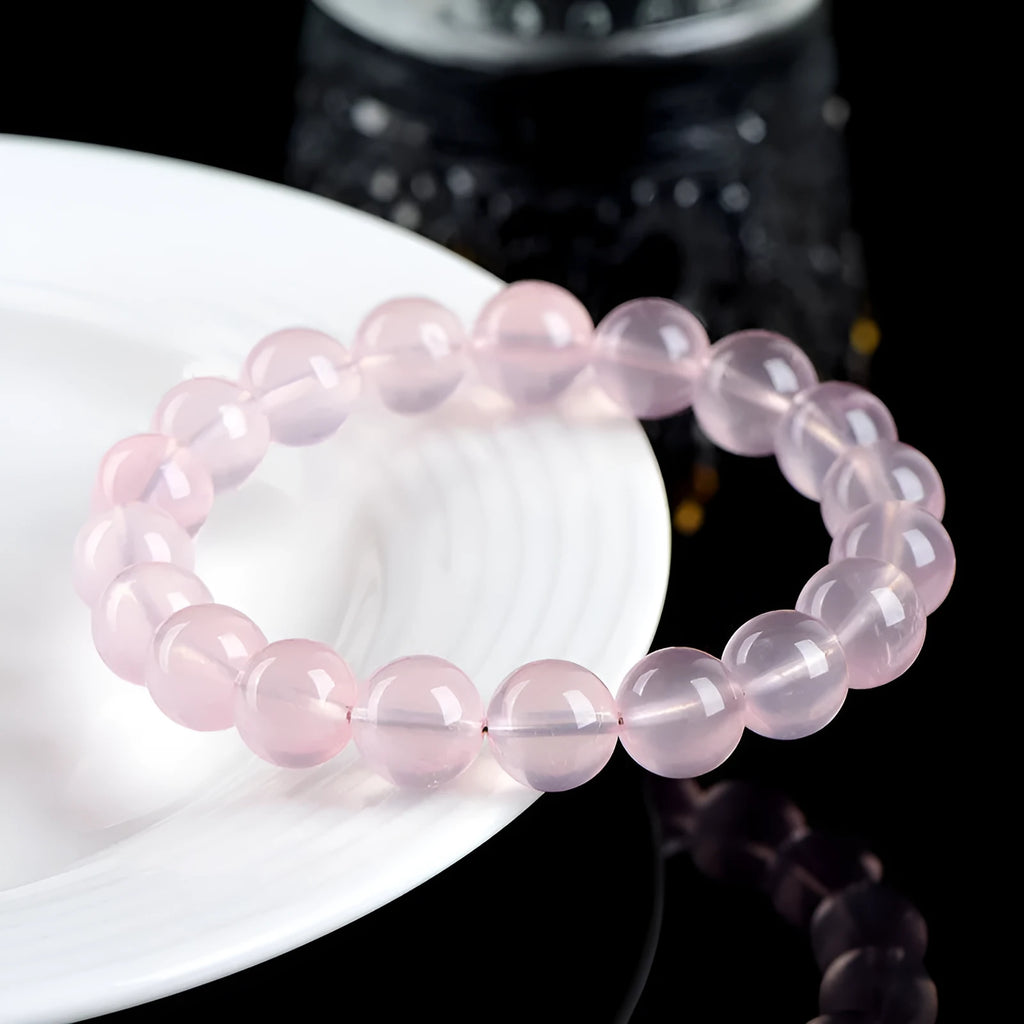 A pink crystal bead bracelet with polished round stones on a single strand.