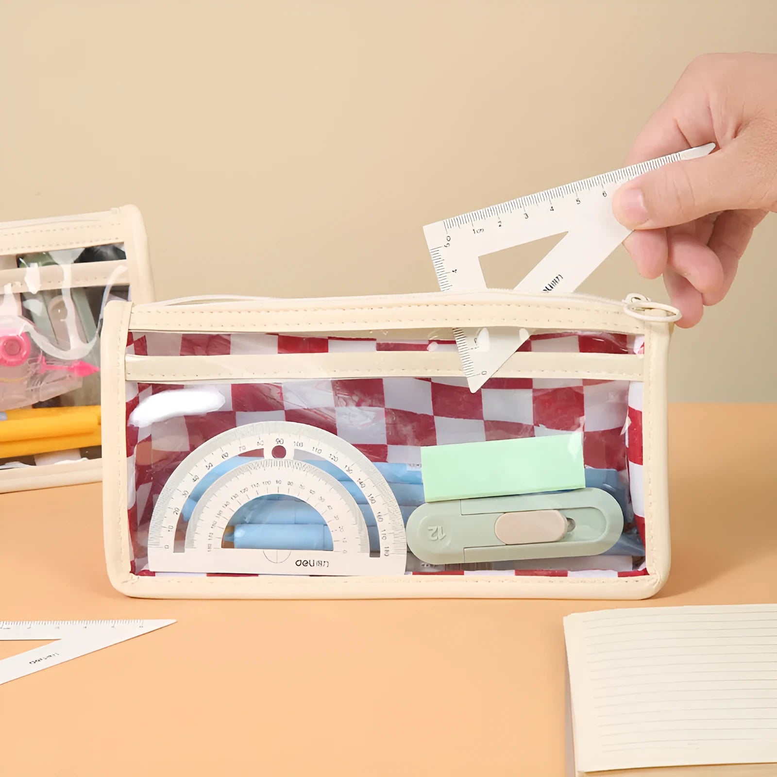 Transparent PVC pencil case with chessboard grid pattern showing pens inside, measuring 21.5cm long