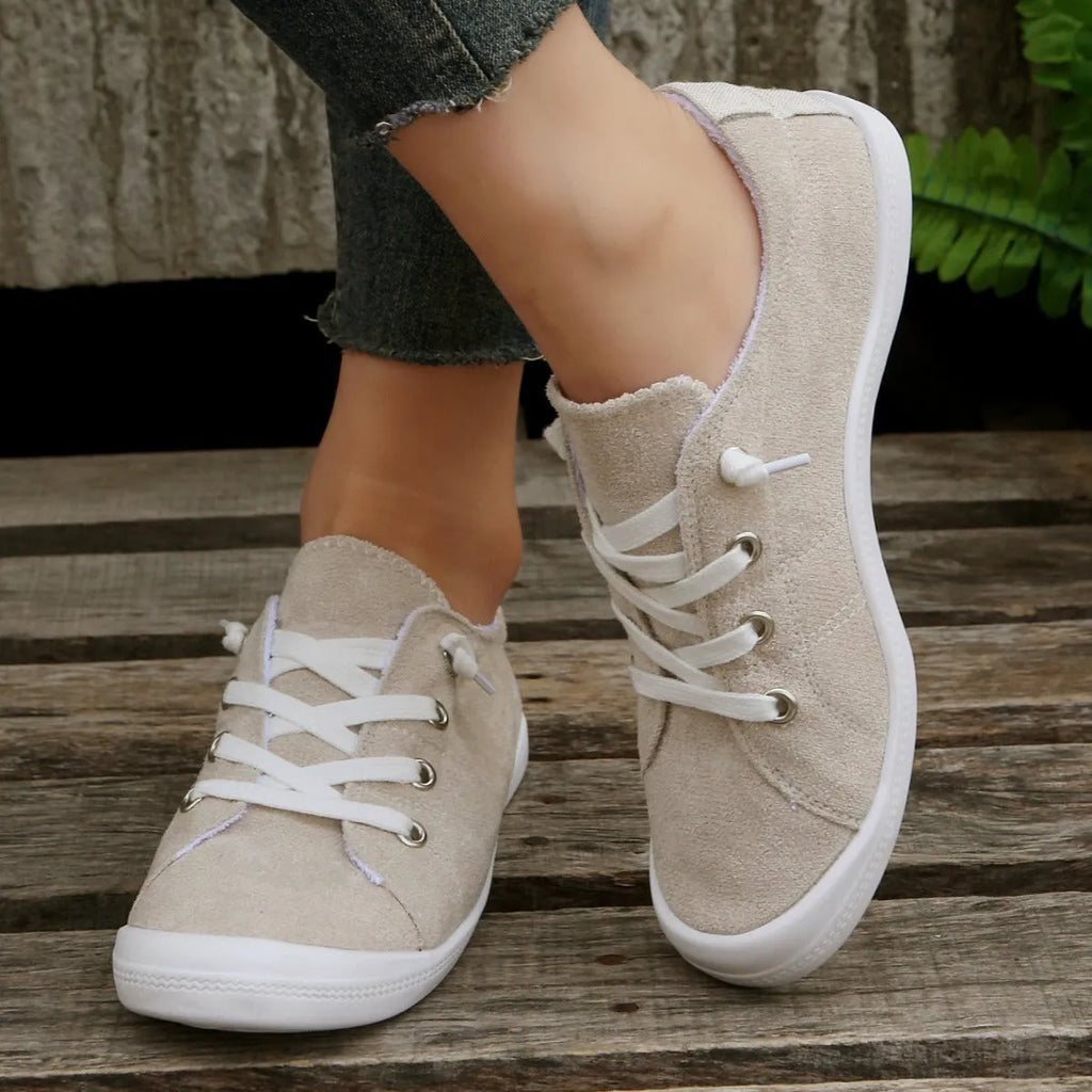 Women's creamy-white low-top fabric sneakers with a rubber sole on a neutral background.