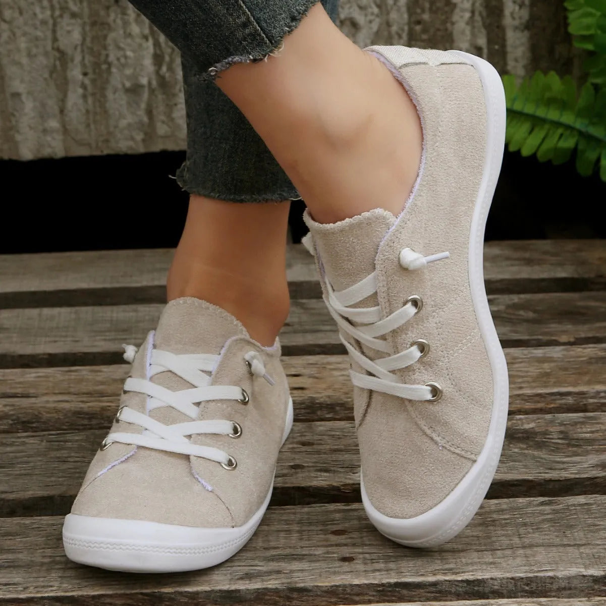 Women's creamy-white low-top fabric sneakers with a rubber sole on a neutral background.