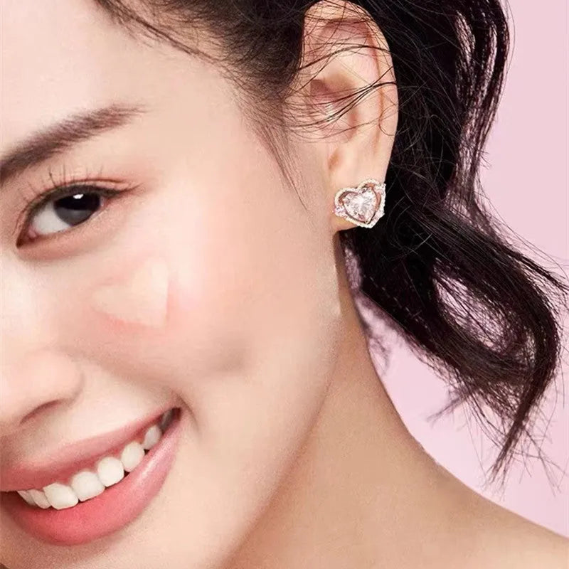 White gold colour heart-shaped stud earrings for women on a jewellery card.