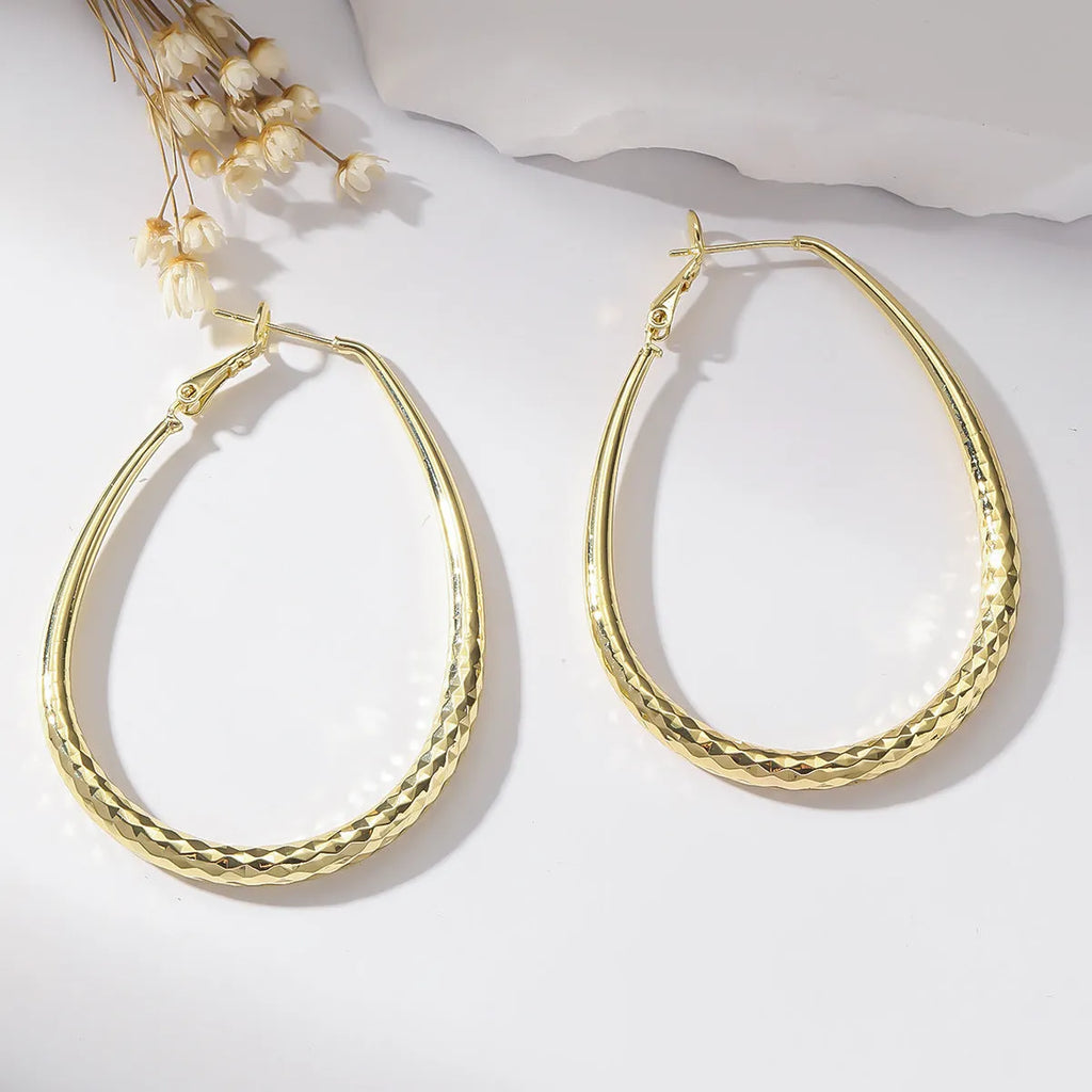Gold egg-shaped copper earrings with hypoallergenic posts and spring fasteners, unisex geometric ellipse design