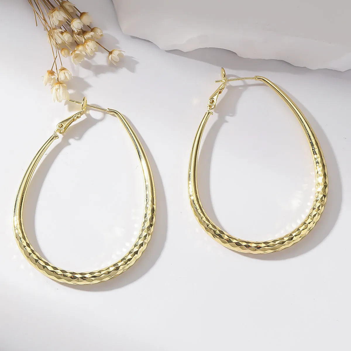 Gold egg-shaped copper earrings with hypoallergenic posts and spring fasteners, unisex geometric ellipse design