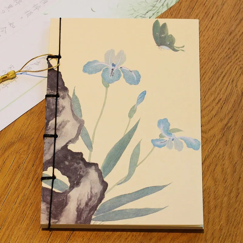 A5 antique wire-bound notebook with glossy embossed cover featuring a retro painting design, shown open.