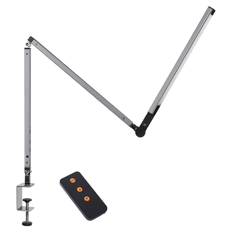 Black folding clip-on LED desk lamp with remote control on a wooden desk.