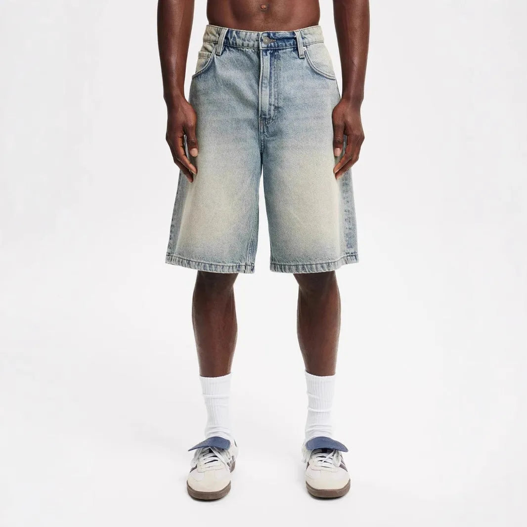 Man wearing loose light blue straight leg cotton denim jeans for casual summer streetwear.