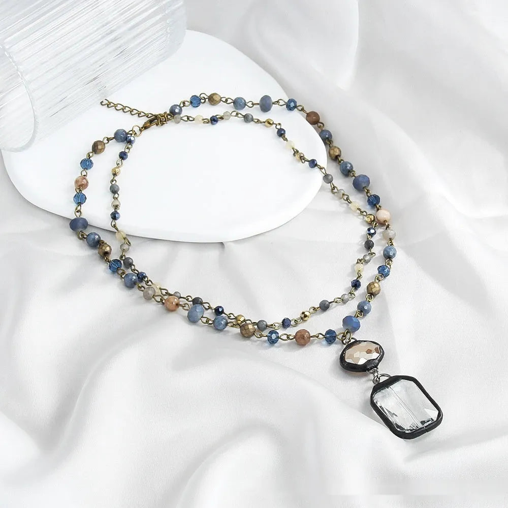 Two-layer tribal-style chain necklace with glass pendant and stone elements in beige and blue colour options