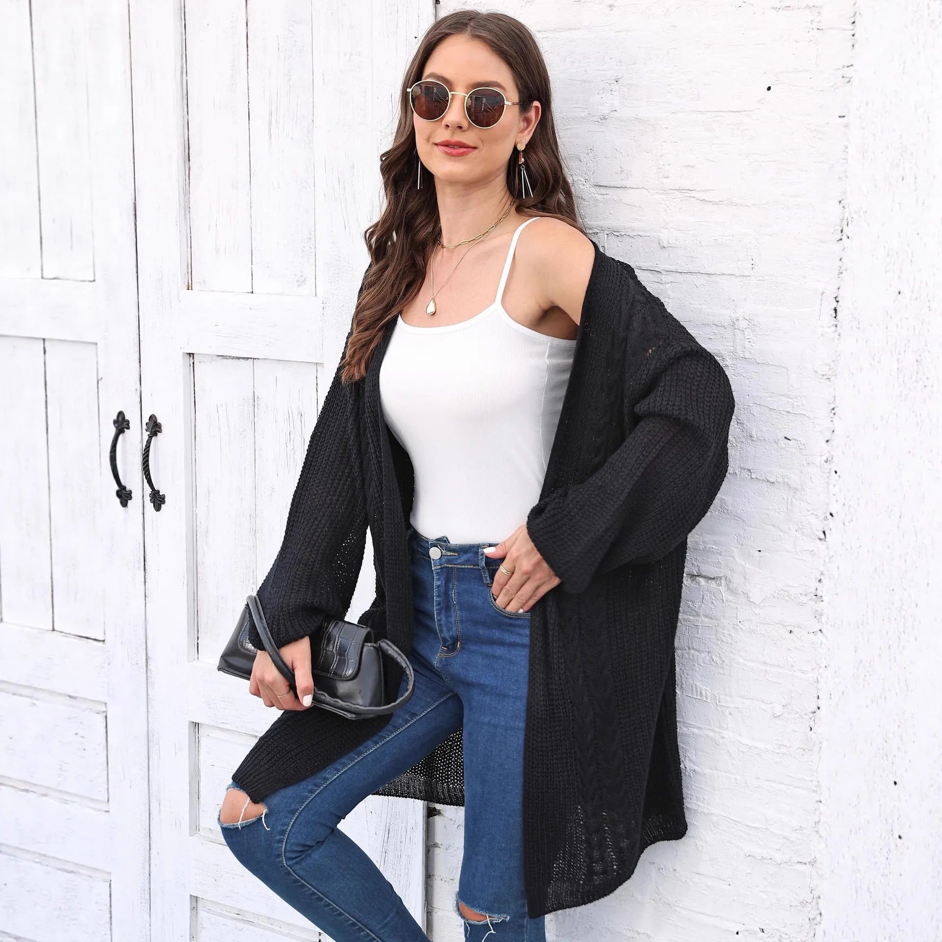 Women's loose-fitting long sleeve acrylic sweater coat in a solid colour on a hanger.
