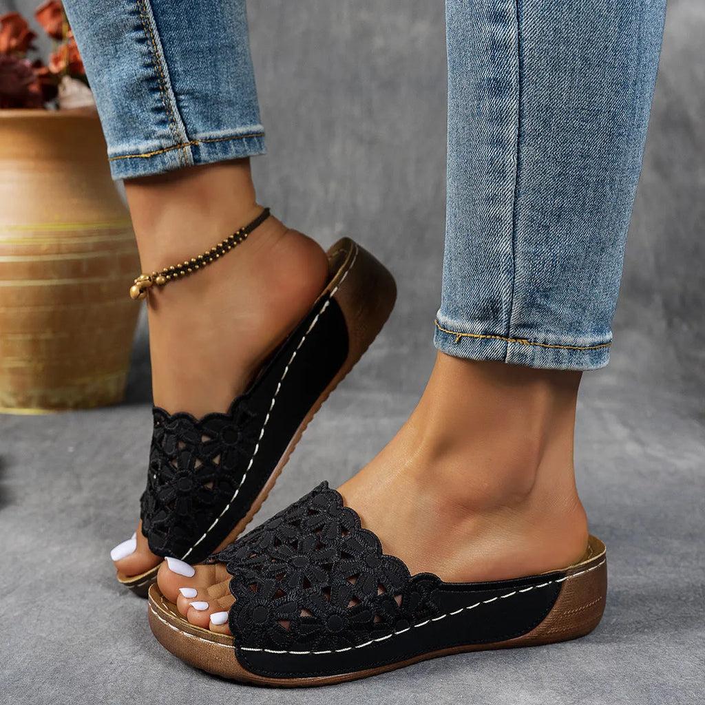 Women's wedge beach slippers with flower cutout design in black colour showing fish mouth toe shape