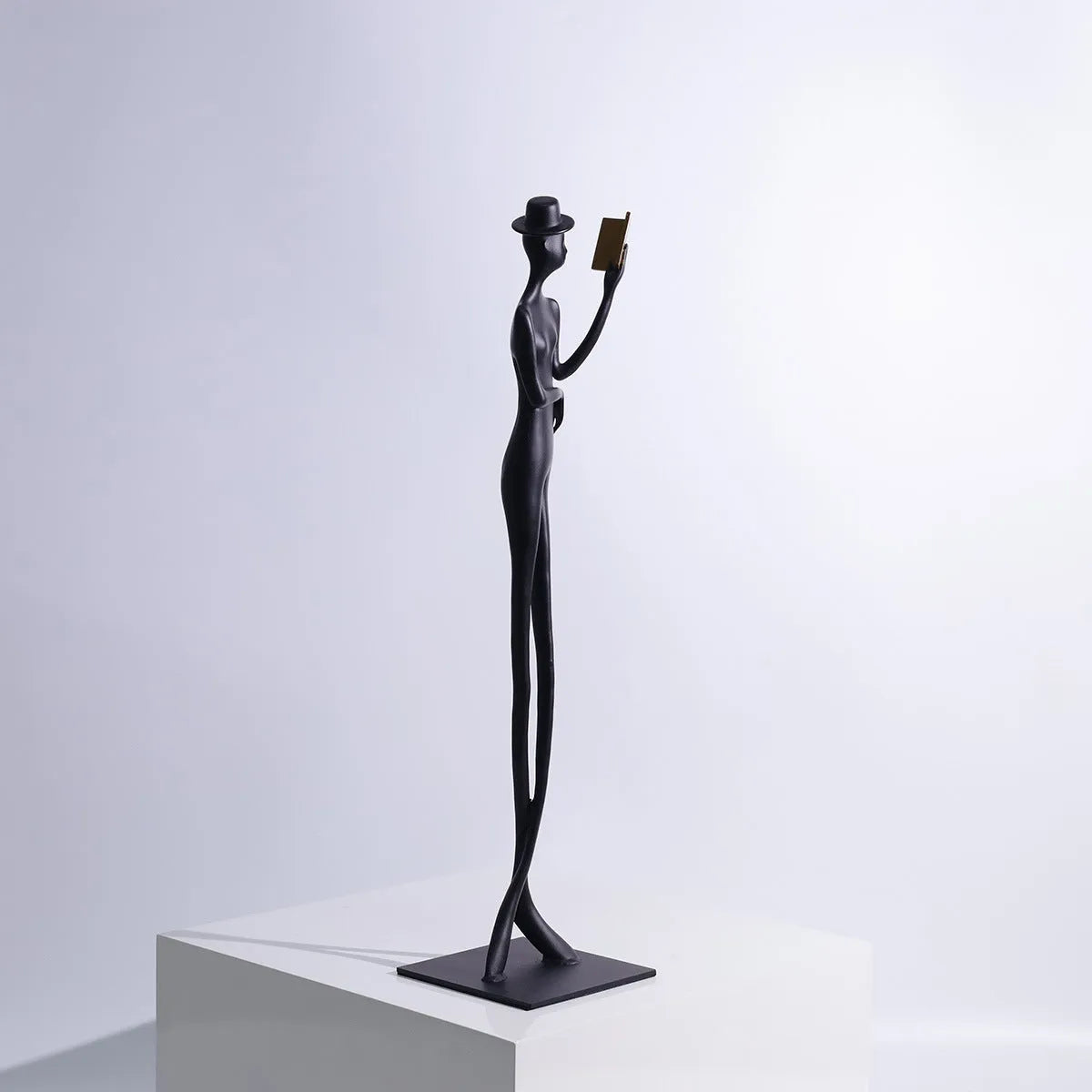 Black cast aluminium desktop sculpture of reading woman figure measuring 12x51cm in modern minimalist style.