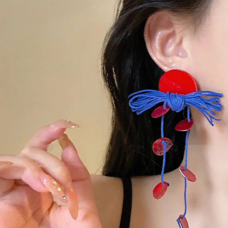 Women's geometric earrings with blue resin flower and silver needle on cloth background