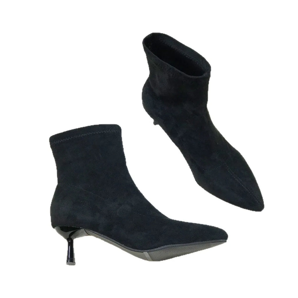Black pointed toe women's ankle boots with a stiletto heel on a plain background