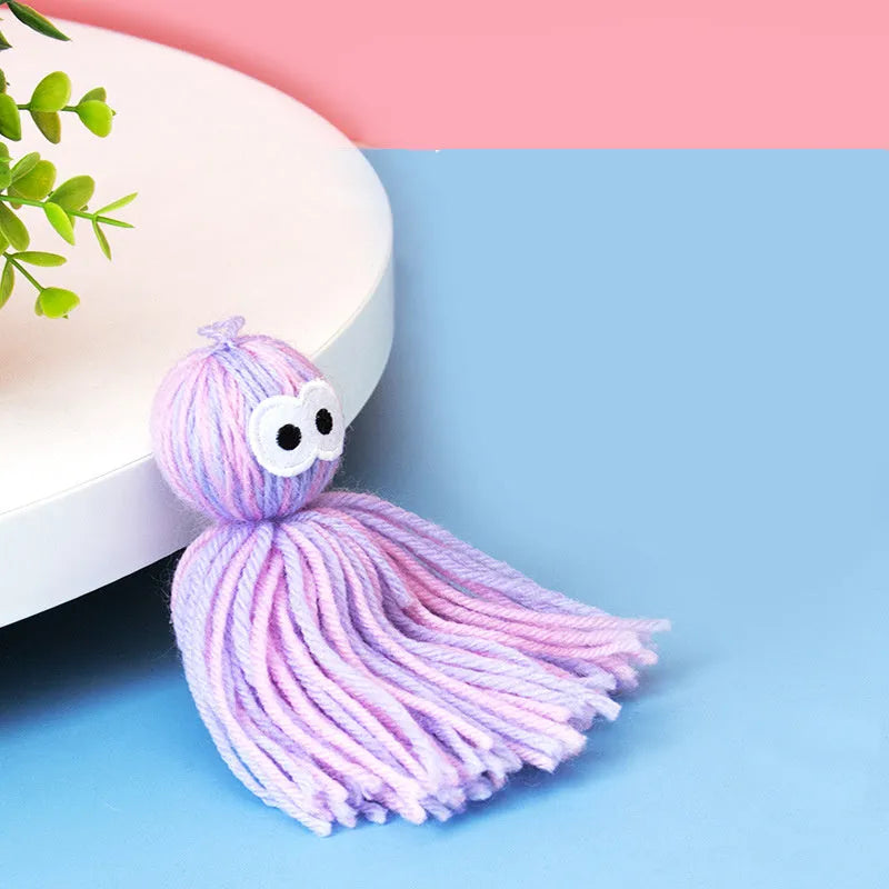 Hanging wool ball cat toy with teaser stick in pink and blue colours on a white background.