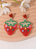 A pair of colourful acrylic earrings with a cake design next to other fruit and ice cream style earrings.