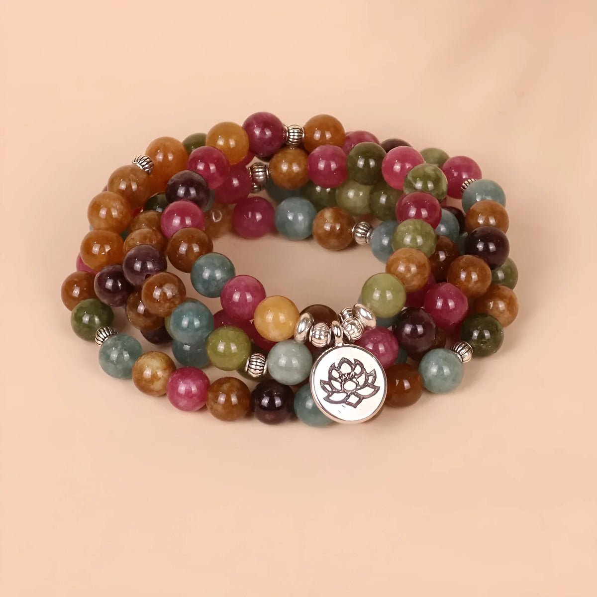 Close-up of a multi-layer beaded bracelet with 108 beads and a hanging lotus charm, made from alloy and tourmaline-coloured material.