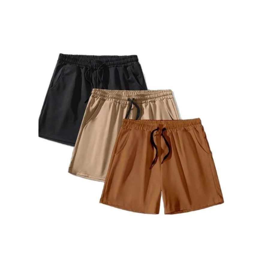 Three pairs of men's solid colour drawstring shorts in black, khaki, and light brown laid flat