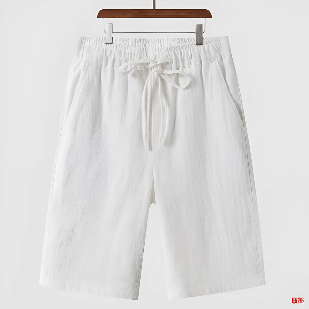 Men's beige linen shorts with a loose cropped fit and mid waistband.