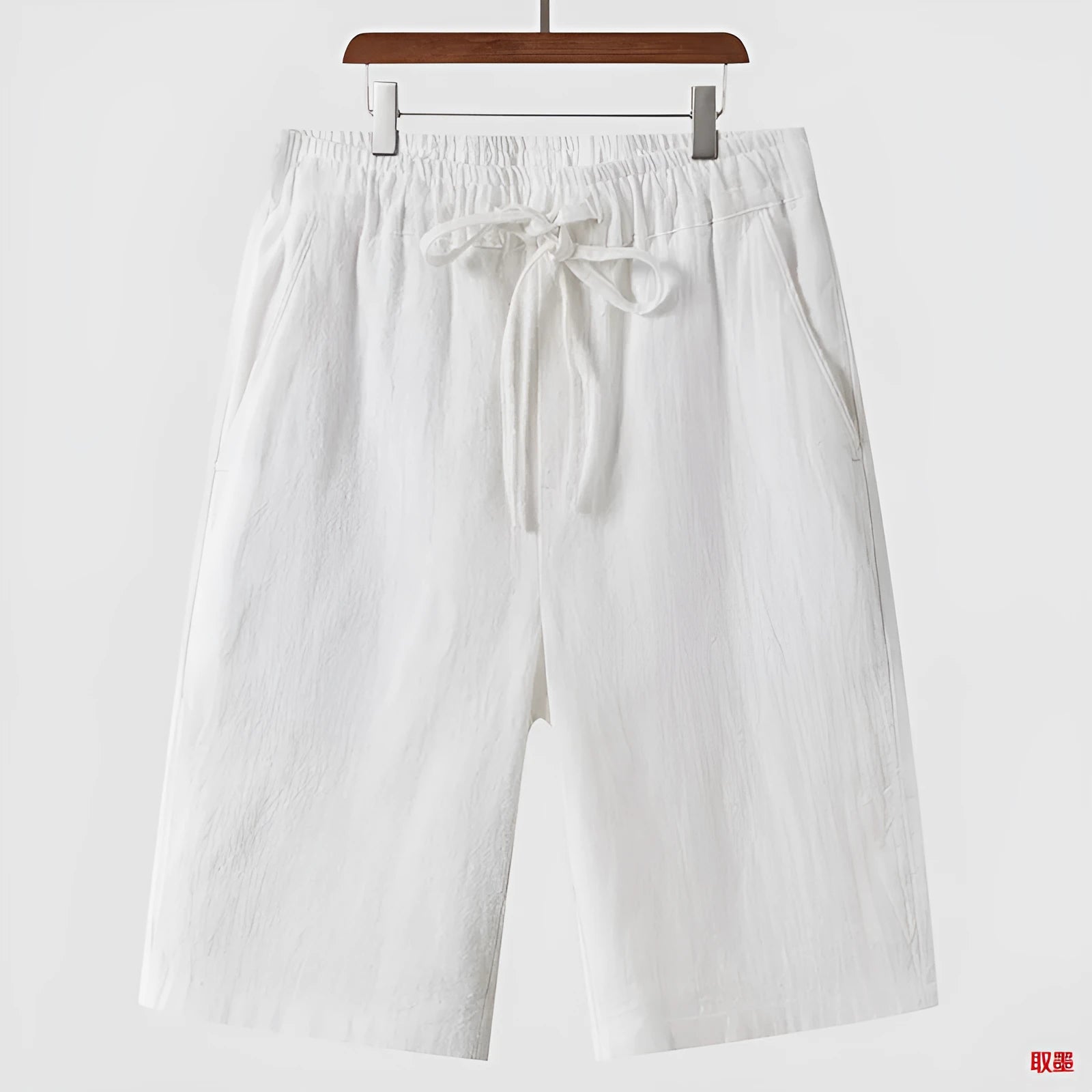 Men's beige linen shorts with a loose cropped fit and mid waistband.