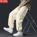 Man wearing grey green loose-fit cotton trousers with stitching print detail and an ankle band.