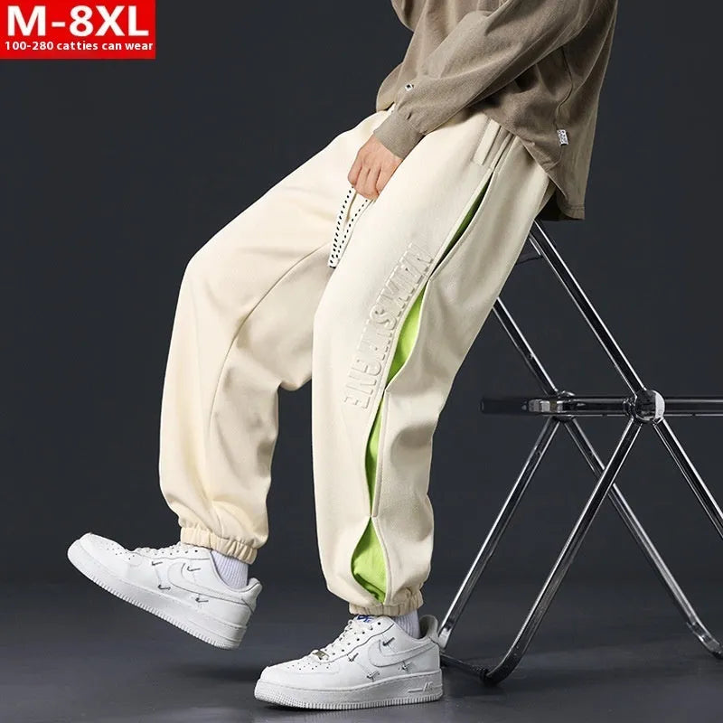 Man wearing grey green loose-fit cotton trousers with stitching print detail and an ankle band.