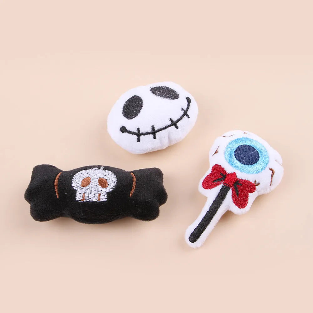 Small plush cat teaser toy in candy, eyes, and skull designs on a blue background.