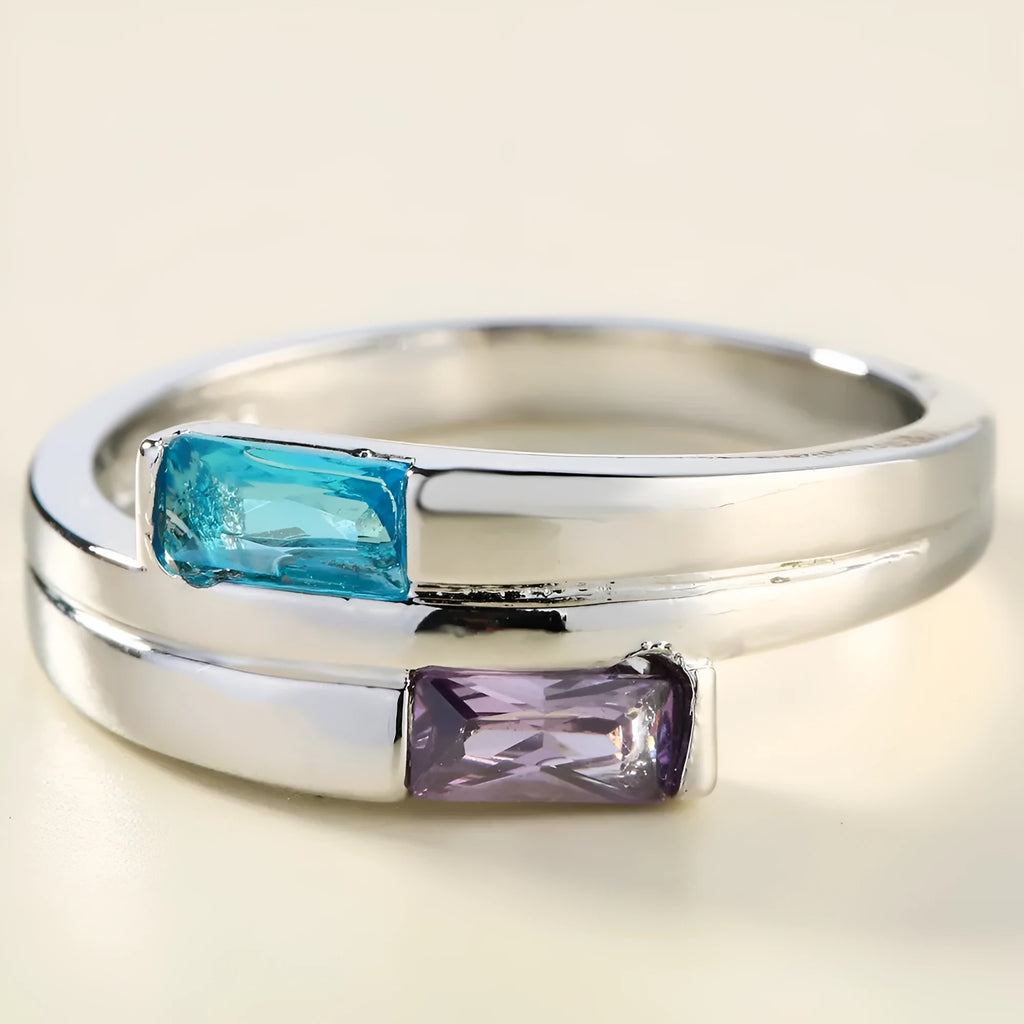 Silver coloured electroplated copper ring with a central inlaid zircon stone on a plain background.