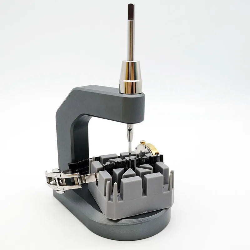 Silver-toned tool steel press strap removal tool for watches and jewellery on a plain background.
