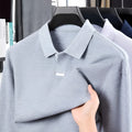 Man wearing a loose-fit grey cotton polo shirt with an asymmetric lapel, long sleeves, and a casual style.