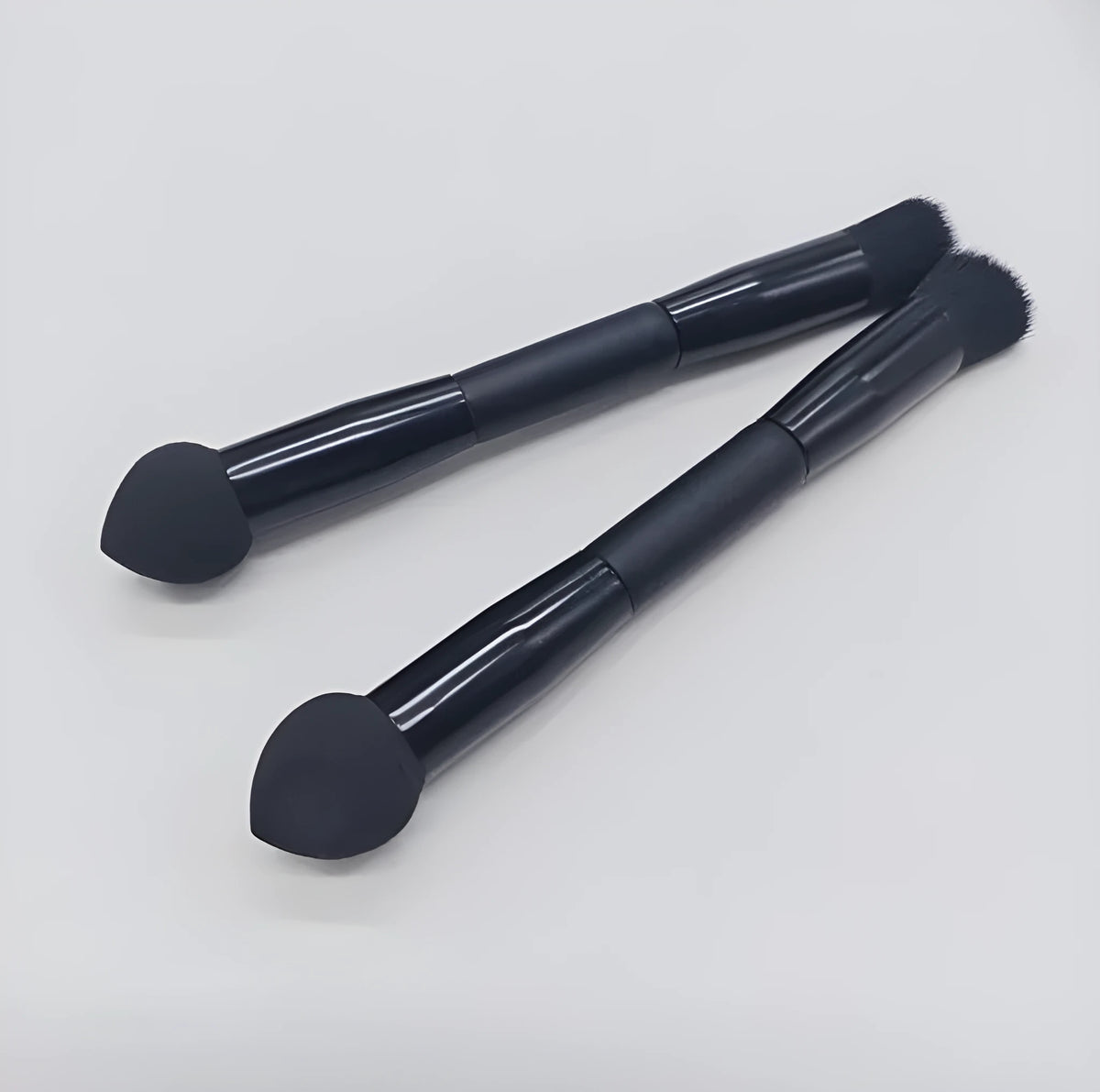 Elegant black double-headed makeup brush with a miter sponge and concealer brush on a wooden handle