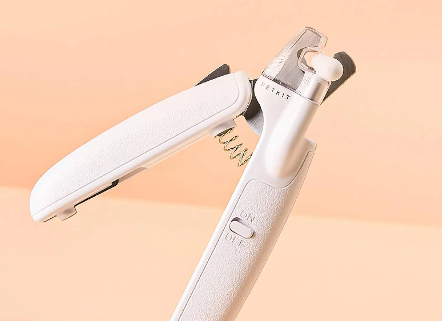 White pet nail clippers with LED light, transparent guard, and leather-like handle next to a nail file.