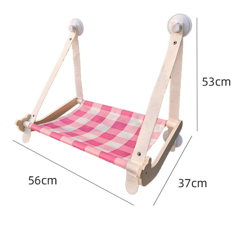 Wooden frame cat hammock with linen mat attached to a window via suction cups, shown in pink colour.