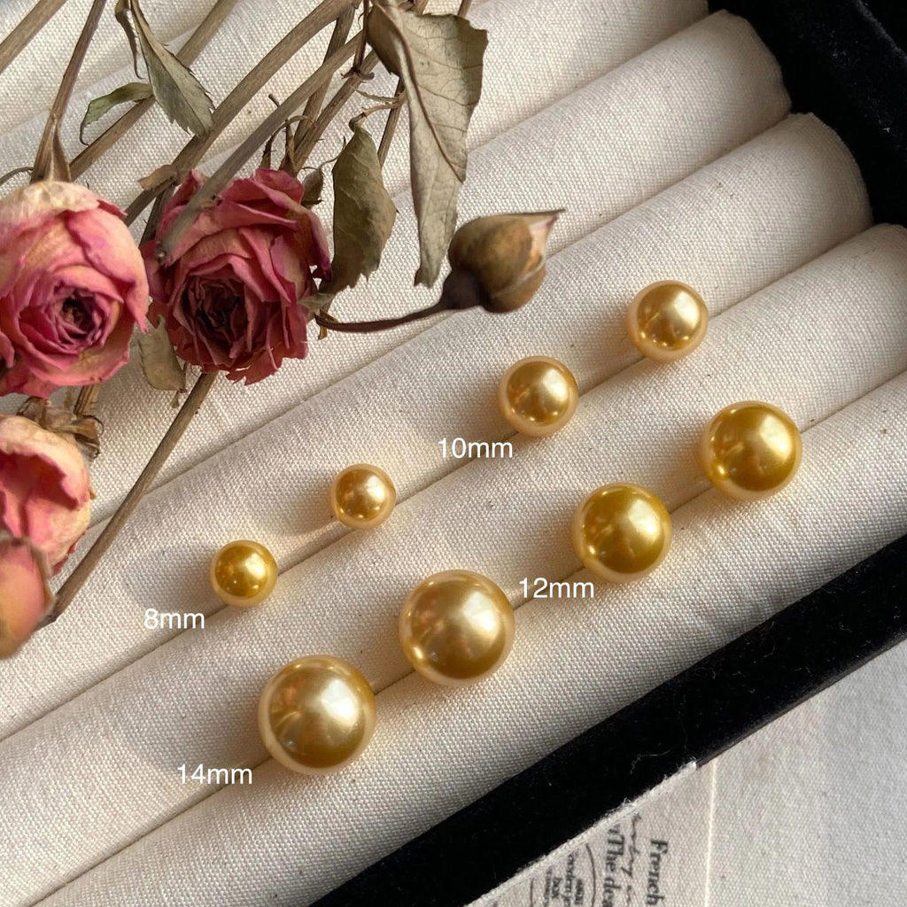 A pair of large geometric pearl stud earrings with an eight-point star detail on a silver setting.