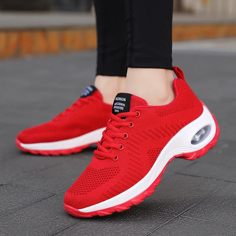 Women's black mesh sneakers with round toe, front lace-up closure, and mid heel on grey background