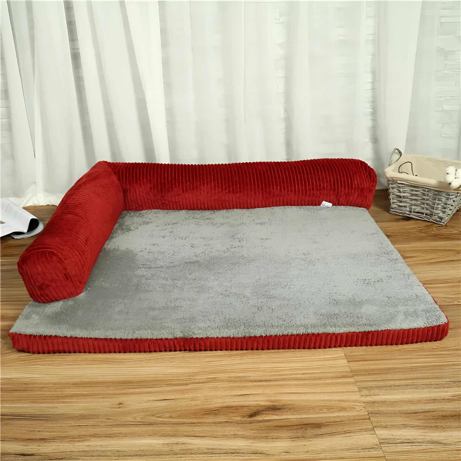 Corduroy pet sofa dog bed with a raised bolster, shown in a grey colour on a wooden floor.