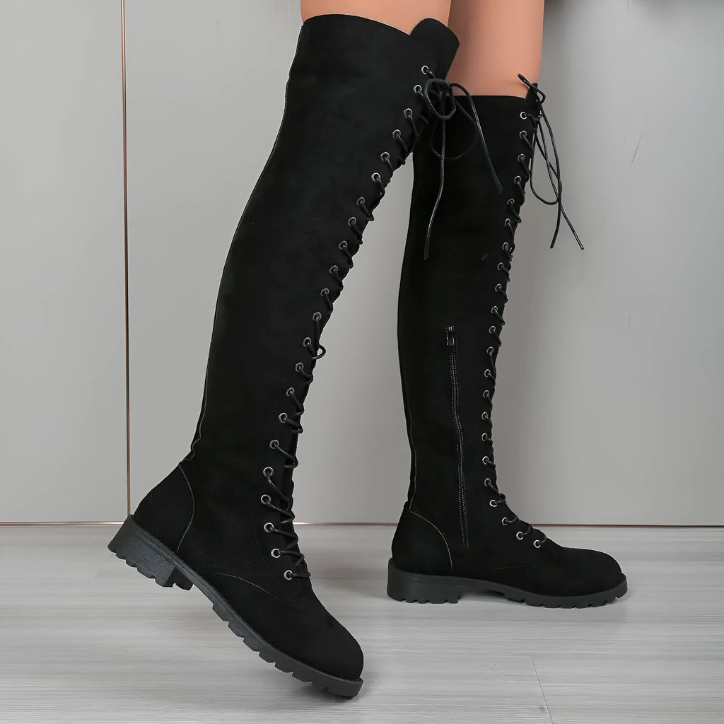 Black lace-up over-the-knee flat boots with round toe and detailed stitching on a white background.