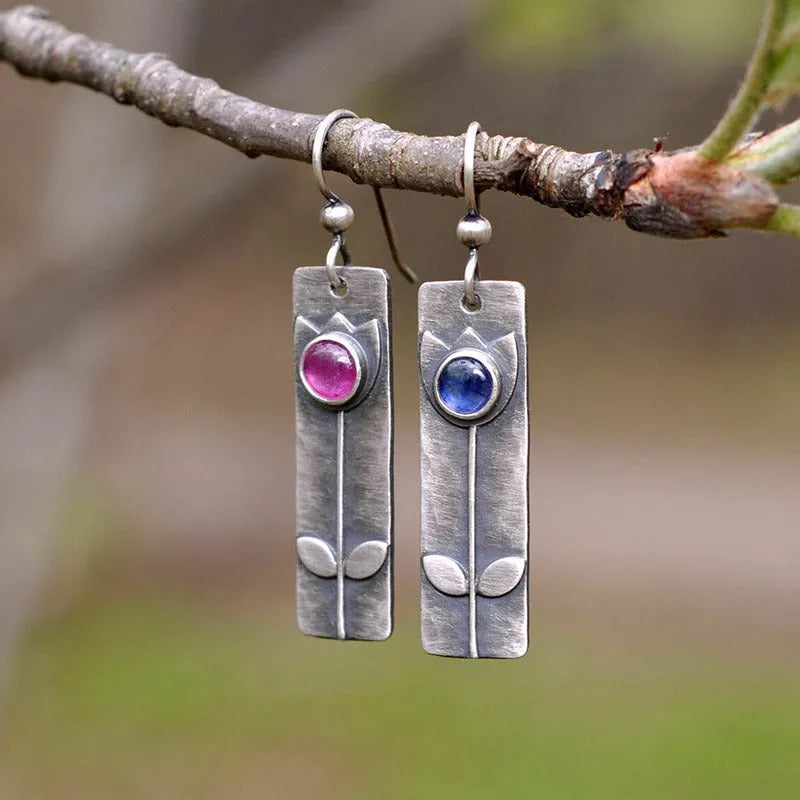 Antique finish red sapphire earrings with elliptical gemstones in a geometric design.
