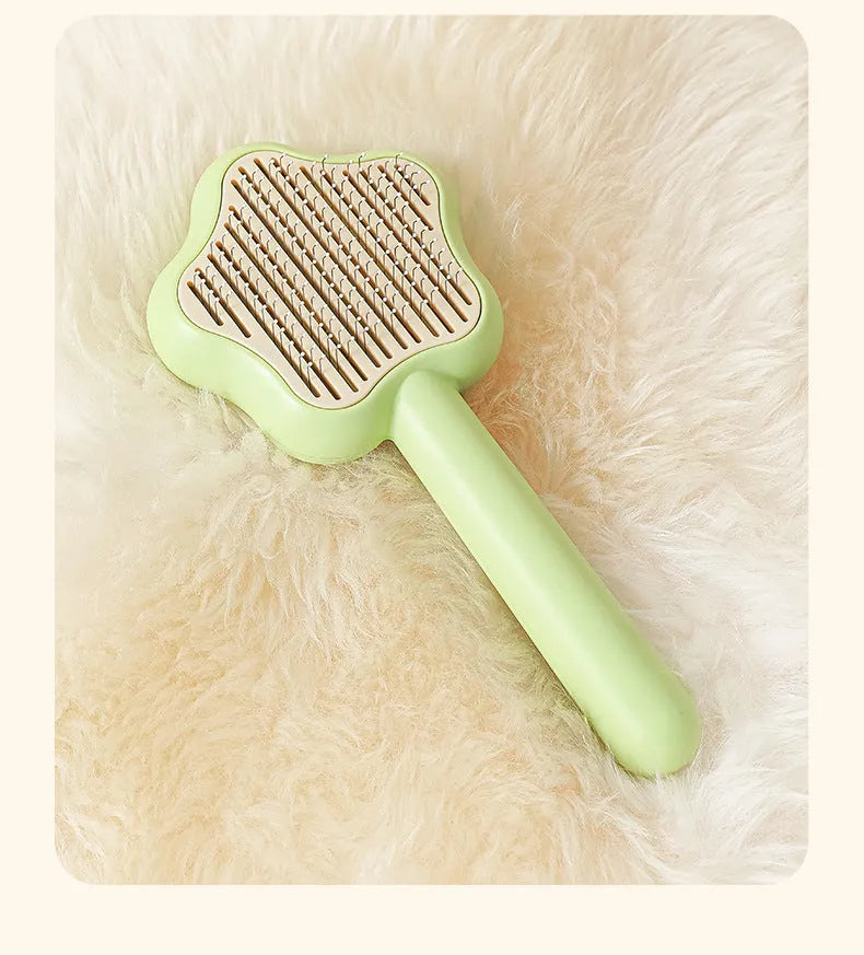 Green self-cleaning cat comb with stainless steel pins on a white background