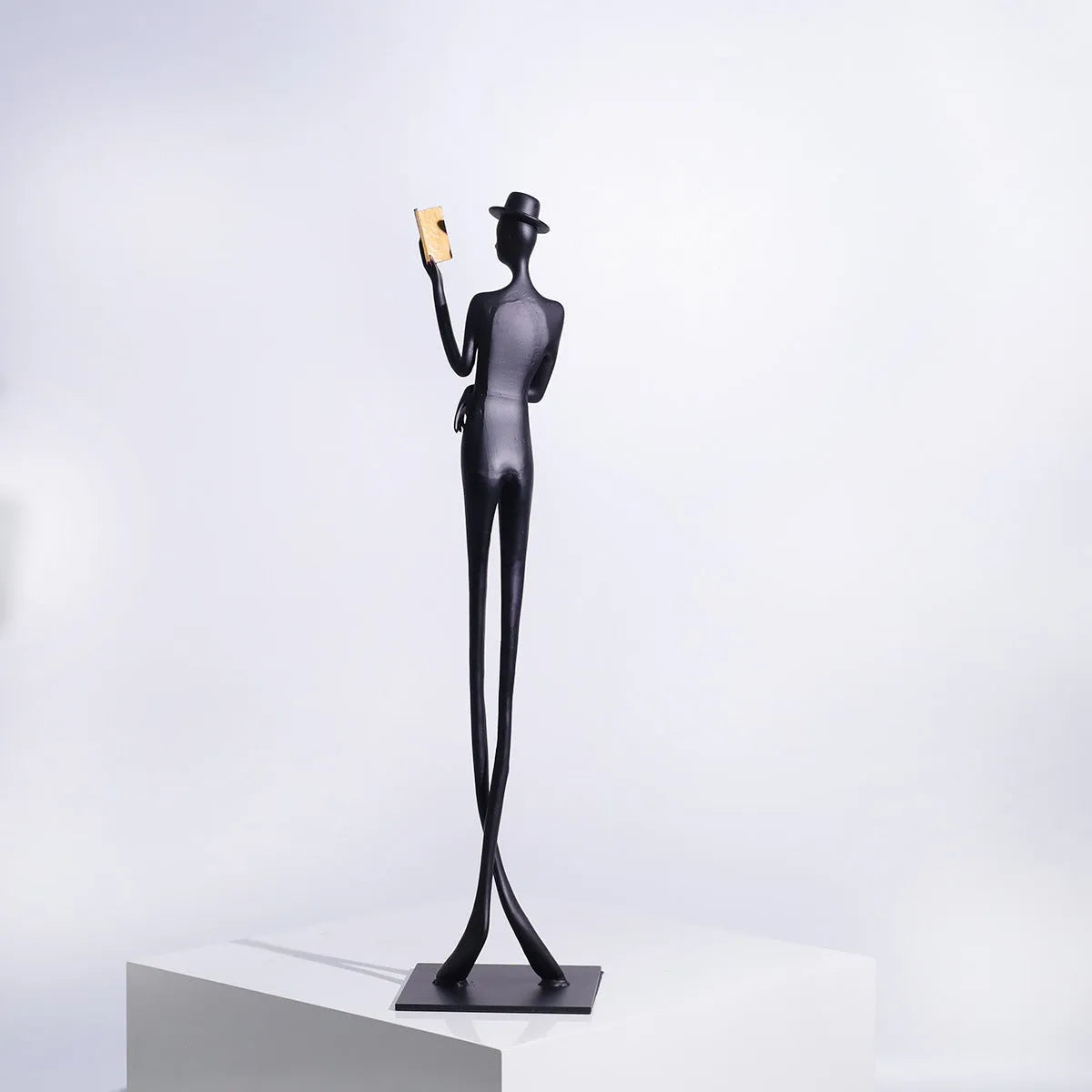 Black cast aluminium desktop sculpture of reading woman figure measuring 12x51cm in modern minimalist style.