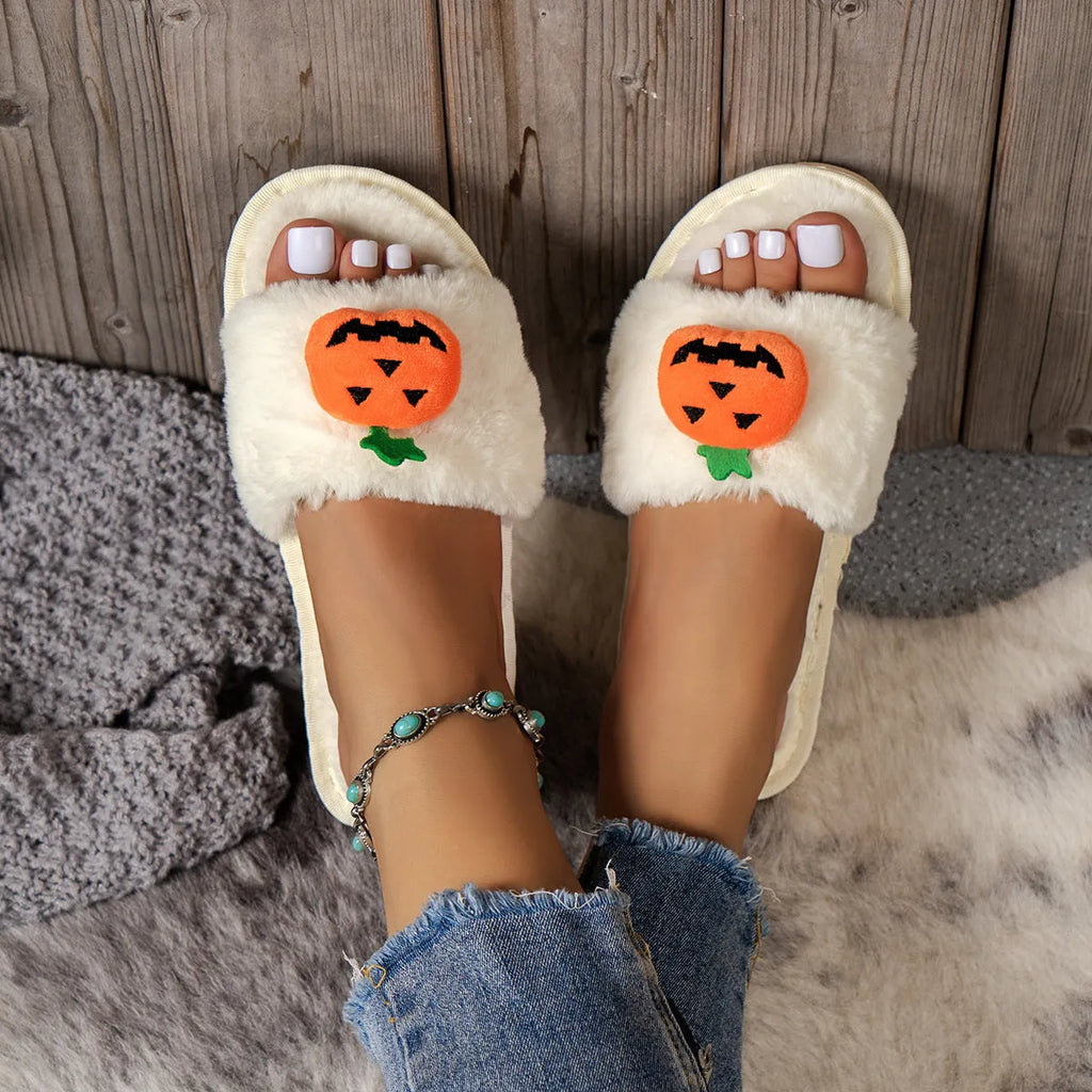 Yellow pumpkin plush open-toe slippers with a cartoon face, shown on a white background.