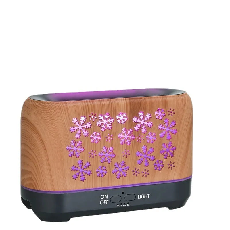 Square snowflake wood grain aromatherapy diffuser showing colourful flame effect mist and remote control on a desktop.